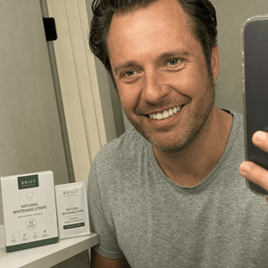 Customer smiling in mirror after whitening strips